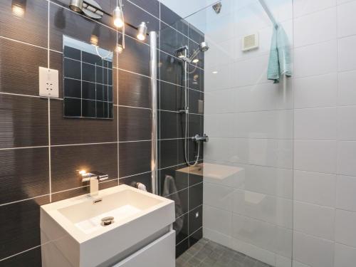 ein Badezimmer mit einem weißen Waschbecken und einer Dusche in der Unterkunft Eller Riggs Cottage in Ulverston