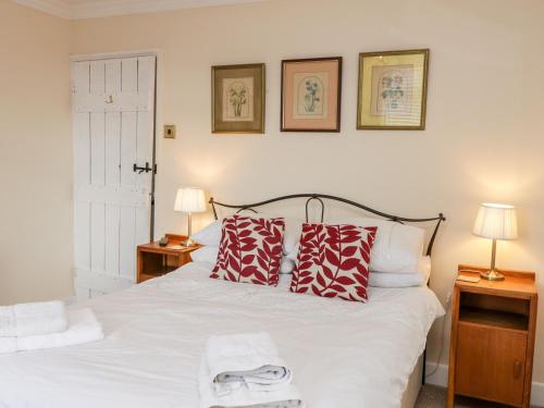 a bed with red and white pillows and two lamps at Yeoman Terrace in Marske-by-the-Sea