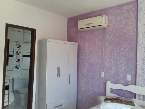 baño con armario blanco y pared púrpura en Apartamento de temporada, en Bombinhas