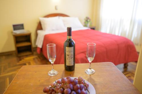 una botella de vino en una mesa con dos copas de vino en Hostel Sol Andina Inn, en Puno