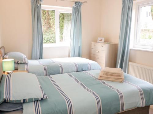 two beds in a bedroom with blue curtains at Treetops in Colwyn Bay