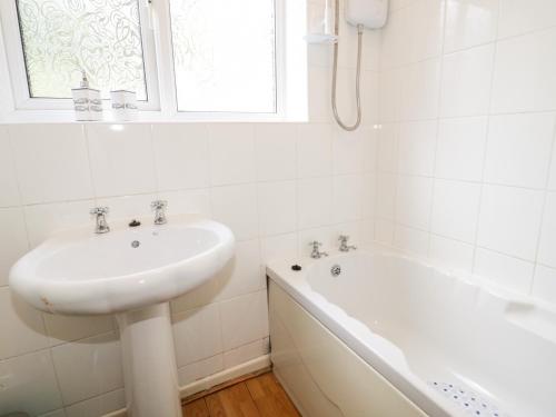 a white bathroom with a sink and a bath tub at Treetops in Colwyn Bay