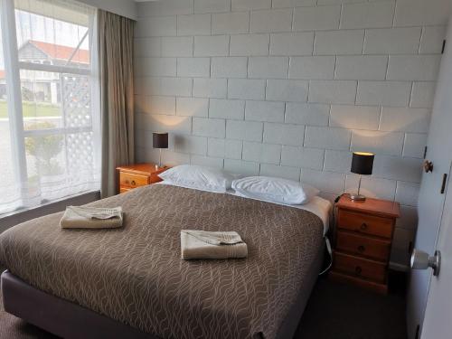 a bedroom with a bed with two towels on it at Kaikoura Motor Inn in Kaikoura