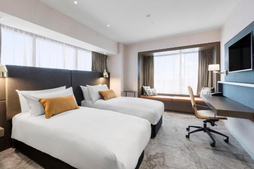 um quarto de hotel com duas camas e uma secretária em Crowne Plaza Christchurch, an IHG Hotel em Christchurch