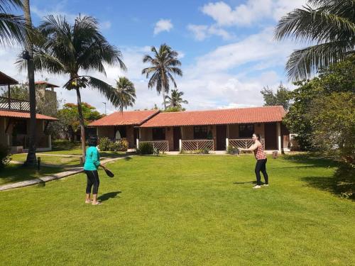 two women playing frisbee in the yard of a house at Arco Mundial Taíba in Taíba