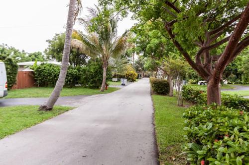 a walkway in a park with palm trees at Comfortable Home, 7 min Walk to Beach, Hot Tub, in Pompano Beach