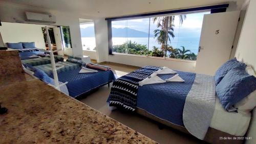 um quarto com 2 camas e uma grande janela em Pousada Refúgio das Estrelas - Vista para o Mar em Ilhabela
