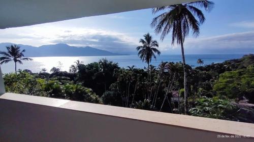 a view of the ocean and palm trees from a house at Pousada Refúgio das Estrelas - Vista para o Mar in Ilhabela