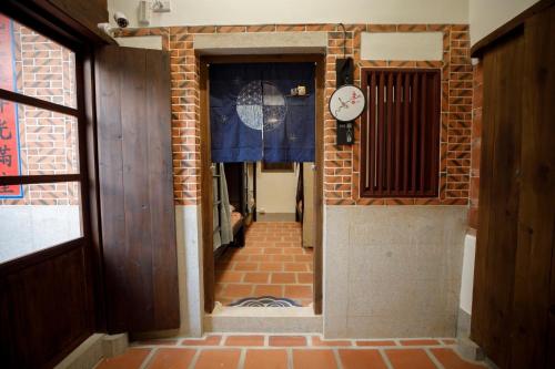 a hallway with a clock on a brick wall at 新龍頭古厝行館 Shin Long Tou B&B in Jinning