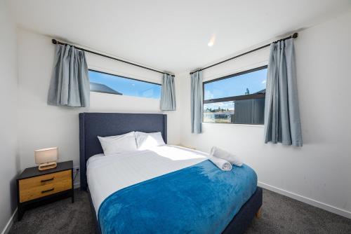 a bedroom with a bed and two windows at Tekapo Top 1000 Apartment in Lake Tekapo