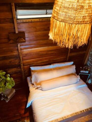 Cama en habitación con lámpara de araña en Rancho Oco Mahogany Loft Type Villa en Nasugbu