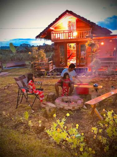 a man and two children are around a camp fire at Rancho Oco Mahogany Loft Type Villa in Nasugbu