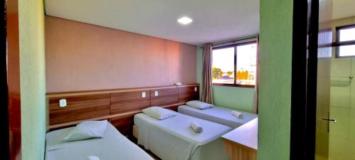 a small room with two beds and a window at Hotel Arterial in Foz do Iguaçu