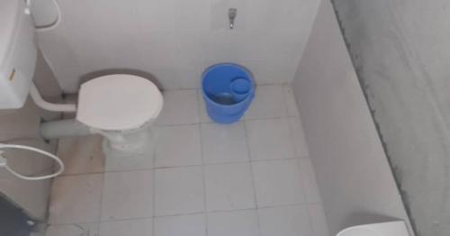 a bathroom with a toilet with a blue trash can at Chanaka Eco Camp ( Adventure Assam ) in Pakariāmukh