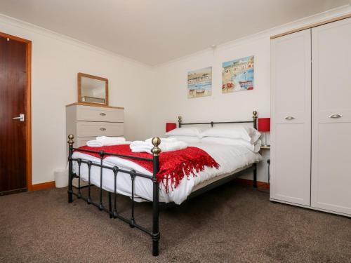 a bedroom with a bed with a red blanket on it at Coach House Cottage in Bude