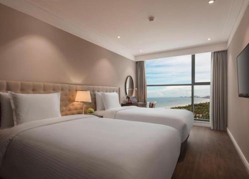 two beds in a hotel room with a large window at Luxury Apartment in Sheraton Building with Ocean View in Da Nang