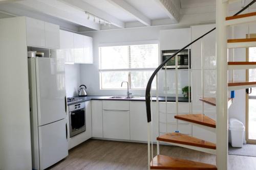 uma cozinha branca com um lavatório e um frigorífico em Dunsborough Beach Shack em Dunsborough