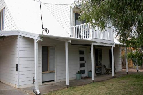a white house with a balcony on top of it at Dunsborough Beach Shack in Dunsborough