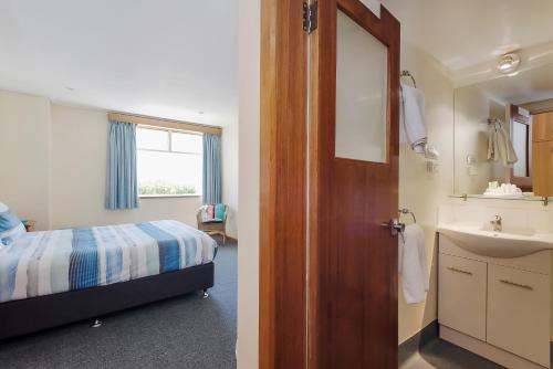 a bedroom with a bed and a bathroom with a sink at Marquis Hotel Motel in Hobart