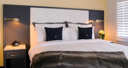 a bedroom with a large bed with black and white pillows at Hotel Marisol Coronado in San Diego