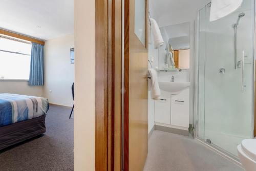 a bathroom with a bed and a shower and a sink at Marquis Hotel Motel in Hobart