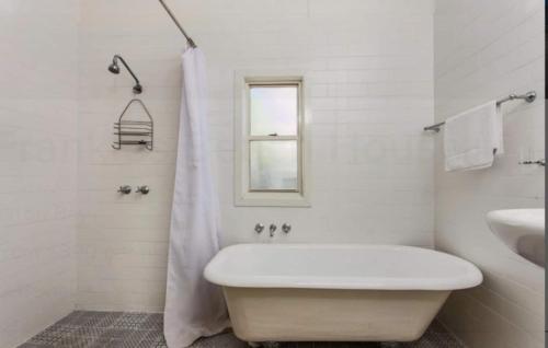 a white bathroom with a tub and a sink at Byron Bay Accom - Frankies Beach House in Byron Bay