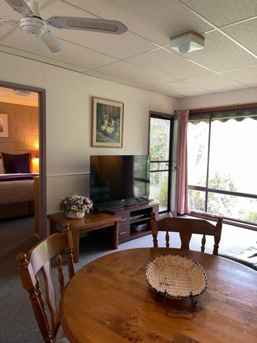 a living room with a wooden table and a television at Forest Lodge Chalets in Bright