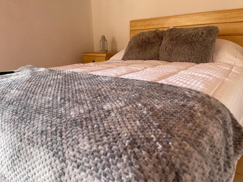 a bed with a gray and white blanket on it at Casa Valentino Trattoria & Alojamiento in Mineral del Monte