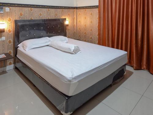 a bed with white sheets and pillows in a bedroom at Homestay Singgasana Mitra RedDoorz in Girian