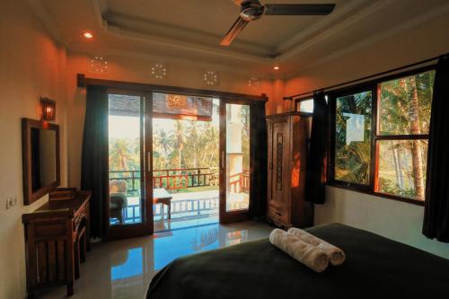 Schlafzimmer mit einem Bett und Blick auf einen Balkon in der Unterkunft Nirwa Ubud Karma in Ubud