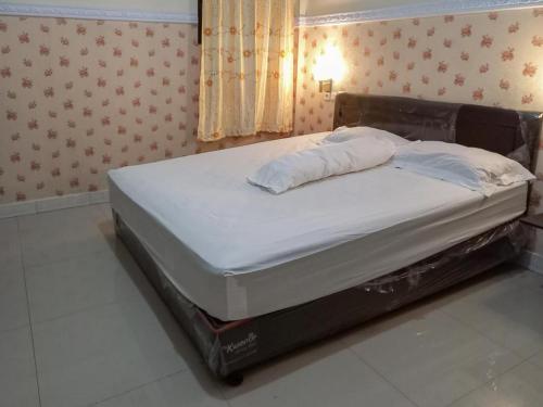 a large bed in a room with avertisementatronatronstrationstrationstrationstrationstration at Homestay Singgasana Mitra RedDoorz in Girian