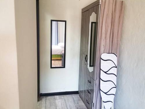 Zimmer mit einer Tür mit einem Spiegel und einem Bett in der Unterkunft Quiet suburb close to OR Tambo International in Boksburg