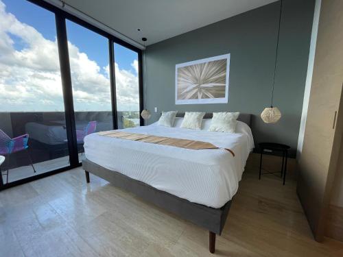 una camera da letto con un letto grande e grandi finestre di Brand New Condo with Rooftop Pool a Cozumel