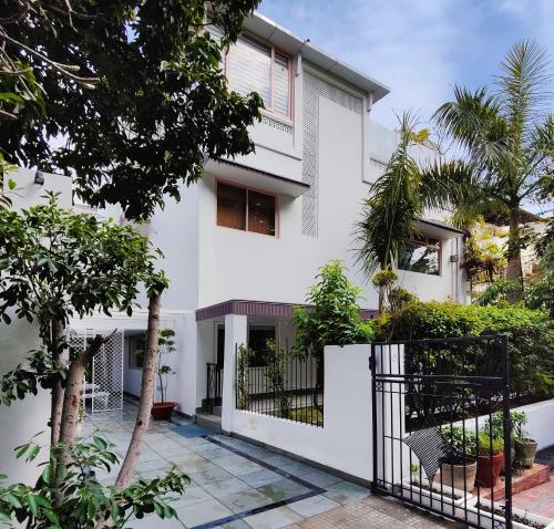 uma casa branca com árvores em frente em Frangipani Suite em Nova Deli