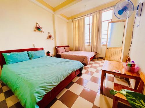 een slaapkamer met 2 bedden en een tafel. bij Nụ Cười Xinh in Da Lat