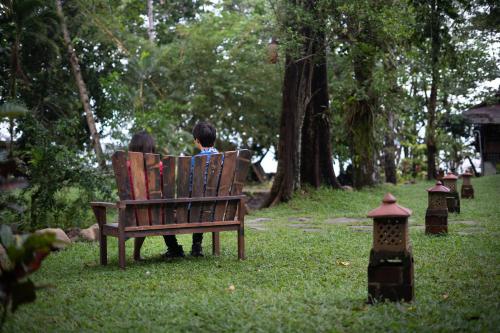 a couple sitting on a bench in a park at Murex Dive Resort in Manado