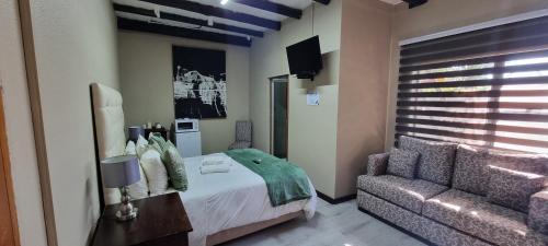 a bedroom with a bed and a couch at Heimat Guesthouse in Welkom