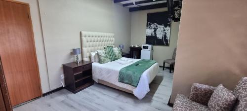 a bedroom with a bed and a table and a chair at Heimat Guesthouse in Welkom