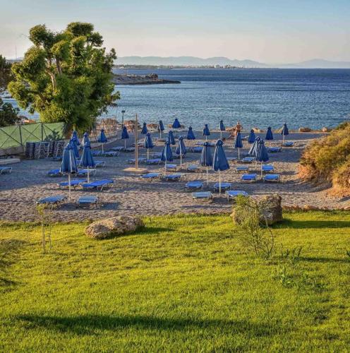 a group of blue umbrellas and chairs on a beach at Kresten Palace Hotel in Kallithea Rhodes