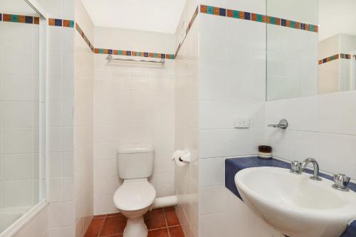 a white toilet sitting next to a bath tub in a bathroom at Majorca Isle Beachside Resort in Maroochydore