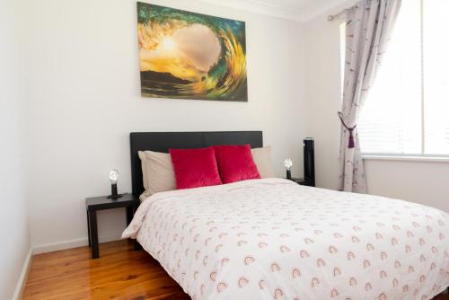 een slaapkamer met een bed met rode kussens en een schilderij bij Le Dar in Orange