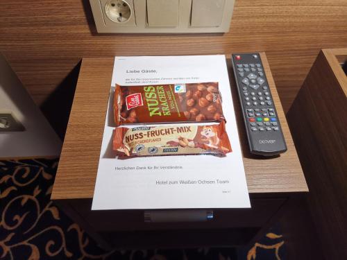 a box of snacks on a table next to a remote control at Hotel zum Weissen Ochsen in Aalen