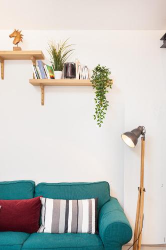 a green couch in a living room with a shelf at Les studios de la faisanderie in Chantilly