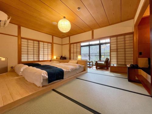 a bedroom with a large bed in a room with windows at Ryokan Nushiya in Gotsu