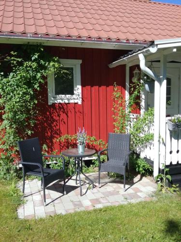 a patio with two chairs and a table in front of a red house at Björkslingan in Vimmerby