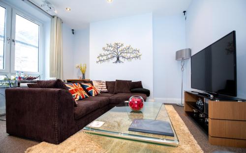 a living room with a brown couch and a flat screen tv at Jay's Apartment Aberdeen in Aberdeen
