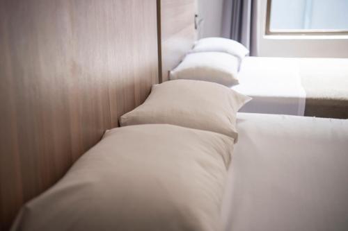 a row of white beds in a room at Ecomotel Kempton Park in Kempton Park