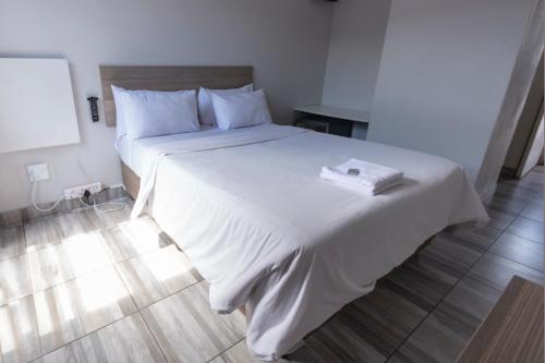a bedroom with a large bed with white sheets at Ecomotel Kempton Park in Kempton Park