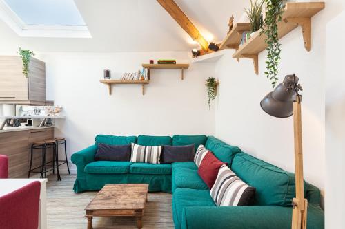 a living room with a green couch and a table at Les studios de la faisanderie in Chantilly