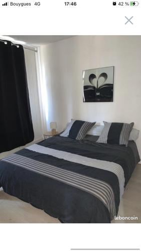 a bedroom with a large bed with black and white sheets at Le petit dieppois in Dieppe